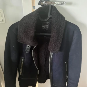 Svart jacka med teddyfoder från Primark - Säljer en svart jacka från Primark med mysigt teddyfoder. Den har en cool krage och dragkedjor på sidorna. Perfekt för höst och vinter när du vill hålla dig varm och snygg. Passar både till vardags och fest!