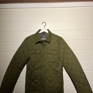 Olivgrön quiltad jacka från Bertoni. - Säljer en snygg olivgrön quiltad jacka från Bertoni. Perfekt för höst och vår med sin stilrena design och praktiska fickor med knappar. Jackan har långa ärmar och en klassisk krage. Passar både till vardags och lite finare tillfällen. 🧥🍂