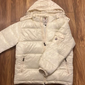 Vit pufferjacka från Moncler - Säljer en snygg vit pufferjacka från Moncler i mycket bra skick. Jackan är använd ett fåtal gånger, sitter som en xl men står M i jackan, säljer billigt eftersom jag har dåligt med pengar just nu, snabb affär.