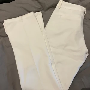 Vita byxor från BikBok - Säljer ett par vita byxor från BikBok i storlek 38. De är lågmidjade och har en snygg bootcut-stil. 
