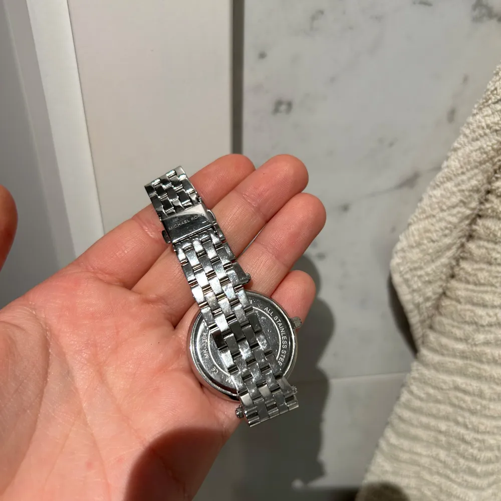 Snygg och elegant klocka från Michael Kors i silverfärg. Den har en glittrig urtavla och ett klassiskt armband i metall. Perfekt för både vardag och fest. Klockan är i mycket bra skick dock behövs batterier bytas ut, därav billigt pris. . Accessoarer.