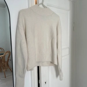 Cremevit stickad tröja - Mysig beige stickad tröja i oversized modell. Perfekt för kyliga höst- och vinterdagar. Tröjan har långa ärmar och ribbade detaljer vid ärmslut och nederkant. Den är superbekväm och lätt att matcha med olika outfits.  Tröjan är inte nopprig. 