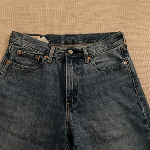 Levi's jeans i blå denim - Säljer ett par klassiska Levi's jeans i blå denim. De har en snygg vintage-look med fem fickor och knappgylf. Perfekta för både vardag och fest! 🕺