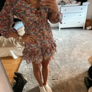 Blommig klänning med volangdetaljer - Säljer en superfin blommig klänning med volanger och v-ringning. 