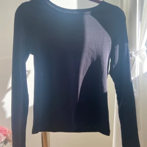 Svart långärmad tröja - Säljer en stilren svart långärmad tröja i bra skick. Perfekt för både vardag och fest. Tröjan har en normal passform och är gjord i ett mjukt material som känns skönt mot huden. Ett måste i garderoben för alla säsonger!