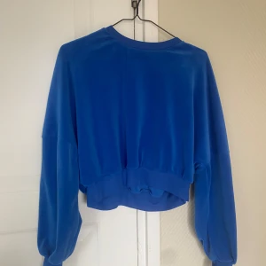Blå croppad tröja - Säljer en superfin blå croppad tröja i mjukt material. Perfekt för en avslappnad stil och passar bra till både jeans och kjol. Tröjan har långa ärmar och en bekväm passform. Perfekt för vår och sommar!