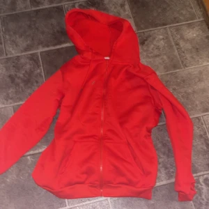 Röd hoodie med dragkedja - Säljer en snygg röd hoodie i bra skick. Den har en praktisk dragkedja framtill och en skön huva. Perfekt för höst och vår när det är lite kyligt ute. Passar både till vardags och träning. OBS! Aldrig använd bara testats