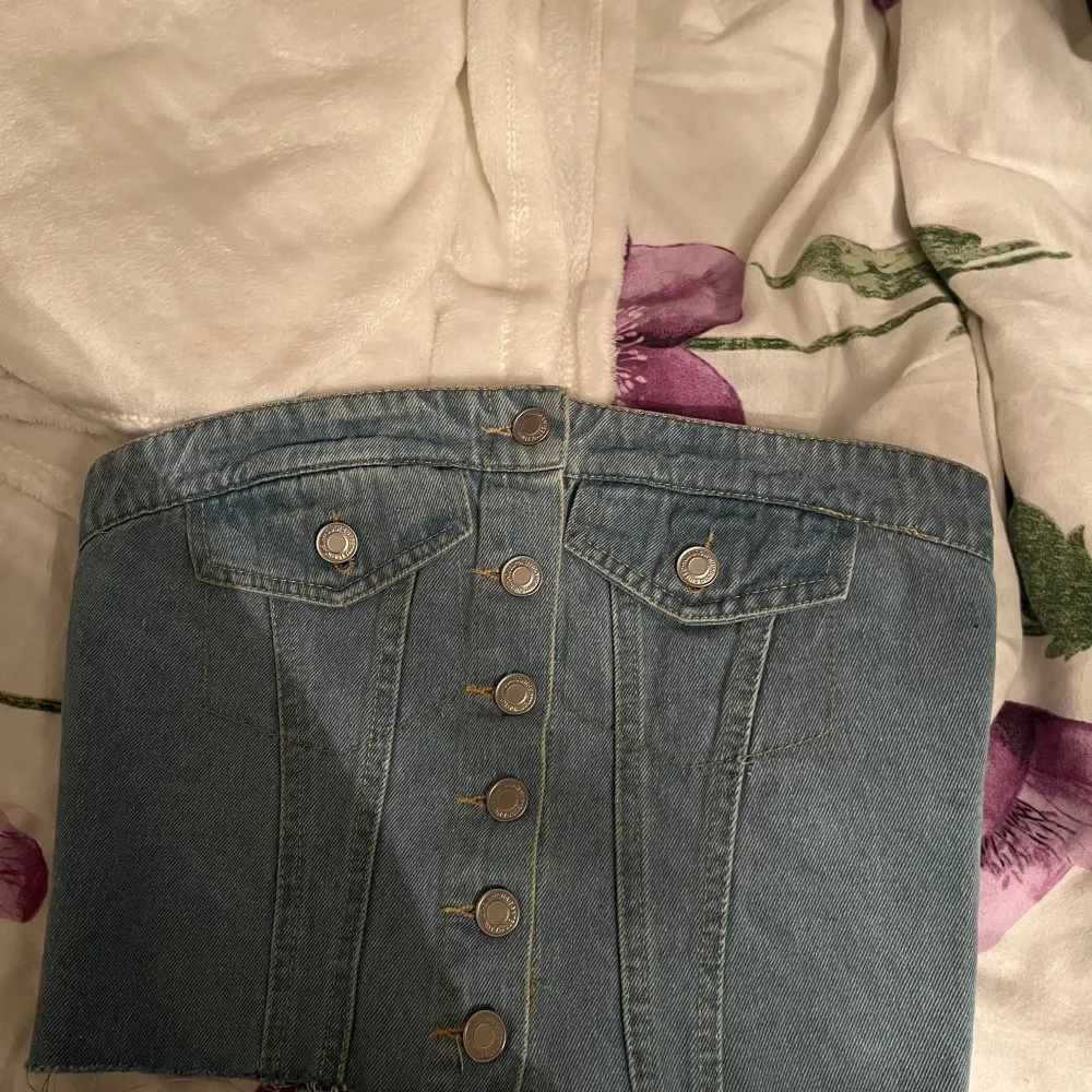 Säljer en superfin jeanstop med snygga knappar framtill. Kjolen har en elastisk del bak för extra komfort och passform. Perfekt för en avslappnad sommarlook eller att styla med en cool topp för fest🩷 Köpte här på plick men den passar inte mig så därför jag säljer.. Toppar.