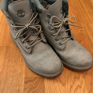 Blå boots från Timberland - Säljer ett par blåa Timberland boots i bra skick. De är vattentäta och har snörning framtill. Perfekta för höst och vinter med sin robusta design och slitstarka material. Skorna har en klassisk look med Timberlands logga på sidan. De är special edition så de går INTE att köpa i butik. Skorna är alltid unika. 