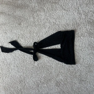 Svart glittrig topp - Snygg svart topp med glittrigt material och knytband i nacken. Helt ny med tag kvar!