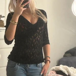 Svart spetsblus - Säljer en elegant svart spetsblus med v-ringning och trekvartsärmar. Perfekt för en utekväll eller fest! Blusen har en tight passform som framhäver figuren och ger en stilren look. Passar bra till både jeans och kjol.