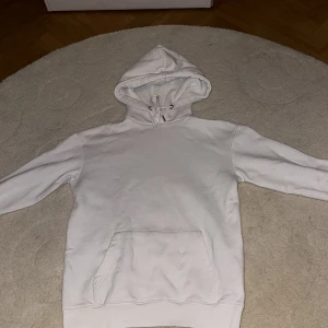 Vit hoodie från Boohoo - Säljer en vit hoodie från Boohoo i storlek XS. Den är supermjuk och perfekt för kyliga dagar. Hoodien har en klassisk design med en stor ficka fram och justerbar huva. Perfekt för en avslappnad stil eller mysiga hemmakvällar. 🕶️ ( har två svarta sträck på höger arm)
