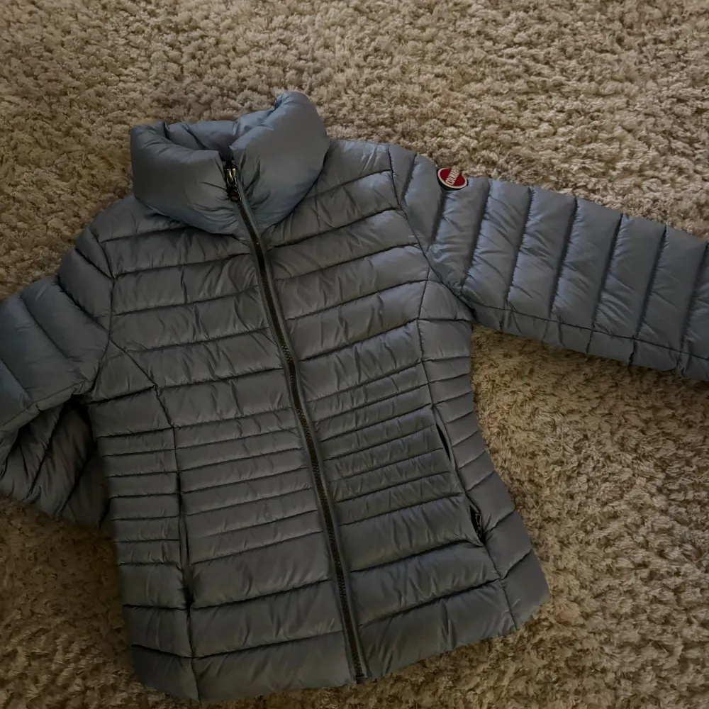 Säljer en snygg och varm blå dunjacka från Colmar i storlek 10 år . Jackan har en dragkedja framtill och är perfekt för kyliga dagar. Den är i mycket bra skick och har en stilren design med Colmars logga på ärmen. Perfekt för både höst och vinter!. Takit.