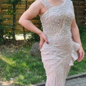 Champagnefärgad pärlklänning - Säljer en fantastisk champagnefärgad klänning med pärlor och volanger. Den är ärmlös och har en elegant, figurnära passform. Perfekt för festliga tillfällen där du vill glänsa! ✨