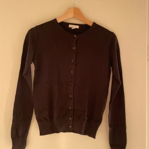Svart kofta från H&M - Säljer en klassisk svart kofta från H&M i storlek XS. Den har långa ärmar och knappar hela vägen fram. Perfekt för både vardag och festliga tillfällen. Koftan är i bra skick och passar till alla säsonger. Ett måste i garderoben! 🖤