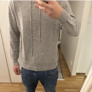 Grå stickad hoodie - Säljer en merino ull hoodie. Storlek L. Riktigt fint skick! Priset är inte hugget i sten. Satt riktigt bra på mig som är 183.