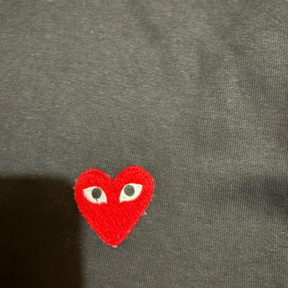 Säljer en svart hoodie från Comme des Garçons i storlek Xl men passar nog även L.med det ikoniska röda hjärtat broderat på bröstet. Den har en dragkedja framtill och är i mycket bra skick. Perfekt för höst och vår, och passar till både vardag och fest. Storleken är inte angiven men den ser ut att ha en normal passform.. Hoodies.