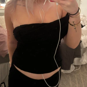 Svart axelbandslös topp - Snygg svart axelbandslös topp i ett stretchigt material. Perfekt för en utekväll eller fest! Den har en tight passform och är croppad, vilket ger en trendig look. Toppen är i mycket bra skick och redo att bäras till nästa event.