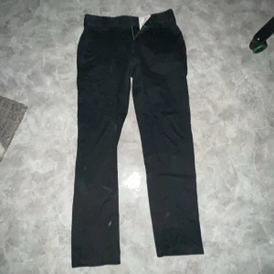 Dickies byxor svarta - Säljer ett par svarta byxor från Dickies i bra skick. De är tillverkade av 65% polyester och 35% bomull, vilket gör dem både slitstarka och bekväma. Perfekta för vardagsbruk eller arbete. Byxorna har en klassisk stil med normal passform.