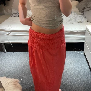 Röd långkjol med resårmidja - Säljer en superfin röd långkjol med bekväm resårmidja. Perfekt för sommardagar eller en avslappnad dag på stan. Kjolen är i ett lätt och luftigt material som gör den skön att bära hela dagen. Passar perfekt med en enkel topp eller linne. 🥰