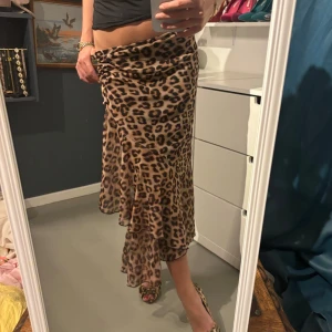 Leopardmönstrad kjol - Säljer en supercool leopardmönstrad kjol i lätt och fladdrigt material. Kjolen har en omlott-design som ger en snygg slits och volangdetaljer längst ner. Perfekt för en utekväll eller fest! 🐆✨