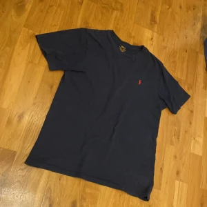 Mörkblå t-shirt från Ralph Lauren - Säljer en snygg mörkblå t-shirt från Ralph Lauren i storlek xl I BARNSTORLEK MOTSVARAR SMALL/MEDIUM. Vanlig passform. Hör av dig vid frågor