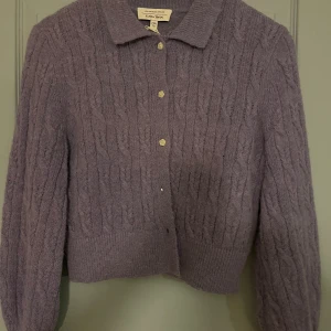 Lila stickad kofta från & Other Stories - Superfin lila stickad kofta från & Other Stories. Den har en klassisk krage och knappar framtill. Perfekt för höst och vinter, och den är i mycket bra skick. Mysig och stilren för alla tillfällen!