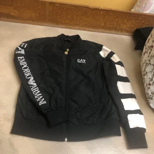 Armani bomberjacka väskor plånböcker, 500kr/st - Säljer en samling av stilrena väskor och plånböcker i olika storlekar och mönster. De flesta är i brunt med monogrammönster och detaljer i beige. Perfekt för både vardag och festliga tillfällen. Plånböckerna är i både vitt och brunt, med snygga geometriska detaljer.