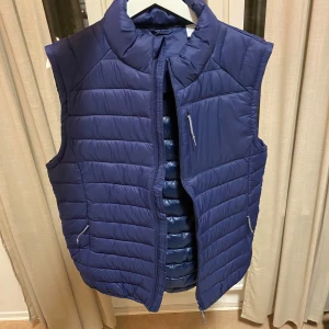 Blå quiltad dunväst - Säljer en snygg blå quiltad dunväst i mycket bra skick