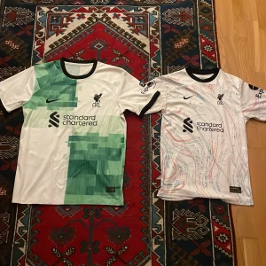 Två fotbollströjor Liverpool - Två Liverpool tröjor. Den gröna är syl M och den vita är stl S/176. 150kr för vardera 
