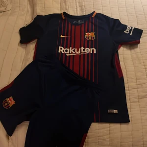 Blå och röd fotbollströja från Nike - Säljer en blå och röd randig fotbollströja från Nike med korta ärmar. Tröjan har klubbens emblem och sponsorlogga på framsidan. Tillverkad i Dri-FIT-material för optimal komfort. Perfekt för fotbollsfans! Har en liten repa byxorna igår i priset. Repan syns inte 🙂
