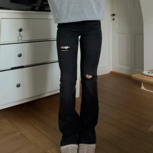 Svarta bootcut jeans med slitningar - Snygga svarta bootcut jeans med slitningar på knäna. Midjemåttet är 35 cm tvärs över och innerbenslängden är 80 cm. Jeansen är köpta second hand men om man ignorera hålen finns det inga fler defekter. Kontakta mig privat vid frågor eller intresse💓