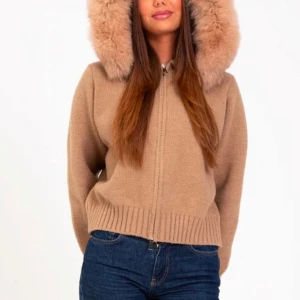 Beige stickad jacka med pälshuva - Snygg beige stickad jacka med en stor och fluffig pälshuva. Jackan har dragkedja framtill och ribbade muddar vid ärmslut och nederkant. Perfekt för kyliga dagar när du vill hålla stilen.