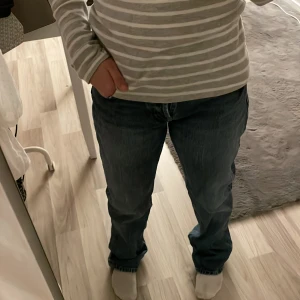 Blå jeans med rak passform - Säljer ett par klassiska blå jeans med rak passform. De har en normal midja och är perfekta för en avslappnad stil. Jeansen har en traditionell femficksdesign och stängs med dragkedja och knapp.