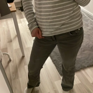 Grå jeansbyxor med knappdetalj - Snygga grå jeansbyxor med klassisk design och knappdetalj i midjan. Perfekta för en avslappnad stil. De har en rak passform och är tillverkade i ett slitstarkt material.