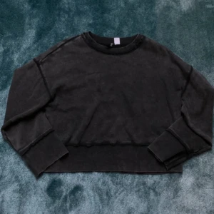 Svart croppad tröja - Säljer en svart croppad tröja med långa ärmar. Tröjan har en avslappnad passform och ribbade detaljer vid ärmslut och nederkant. Perfekt för en casual look.