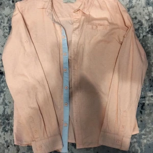 Ljusrosa skjorta från Zara - Säljer en stilren ljusrosa skjorta från Zara. Skjortan har långa ärmar och knappar framtill. Perfekt för en avslappnad men ändå uppklädd look. Passar bra till både jeans och chinos.