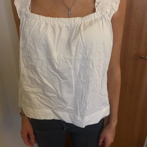 Vit ärmlös topp från MNG - Säljer en söt vit ärmlös topp från MNG med volangdetaljer vid axlarna. Toppen har en lös passform och är perfekt för varma dagar. Den är tillverkad i ett lätt och bekvämt material och är väldigt bekväm! Har nästan aldrig använt den och är i toppen skick!