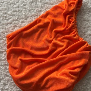 Orange topp - Snygg topp i stretchigt material med en enkel design. Perfekt för soliga dagar. Tillverkad av 95% polyester och 5% spandex för en bekväm passform.