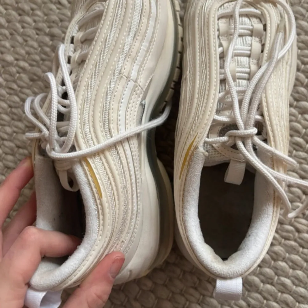 Säljer ett par vita Nike sneakers med synlig luftdämpning i sulan och klassisk snörning. Skorna har en stilren design med Nike-loggan på sidan.. Kengät.