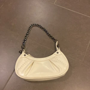 Beige/vit axelväska från Gina Tricot - Snygg beige axelväska från Gina Tricot med kedjehandtag och dragkedja upptill💕