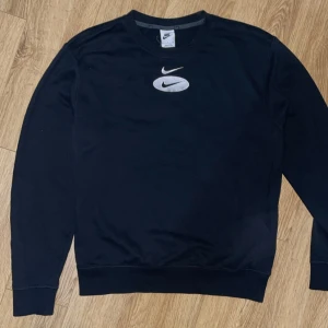 Svart tröja från Nike - Säljer en svart tröja från Nike med deras ikoniska logga i silver på både fram- och baksidan. Tröjan har långa ärmar och en klassisk rund halsringning. Perfekt för en sportig look eller avslappnad stil. 🖤