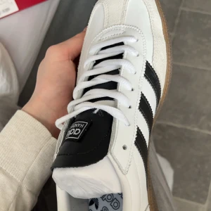 Adidas Spezial sneakers - Snygga Adidas Spezial sneakers i vitt med svarta ränder och gummisula. Skorna har klassisk snörning och en stilren design med gulddetaljer. Perfekta för en sportig och trendig look.