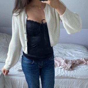 Vit stickad kofta från Zara - Säljer en ben vit stickad kofta från Zara. Koftan har långa ärmar och knappar framtill, perfekt för lager-på-lager-stil. Passar bra till både jeans och klänningar. 