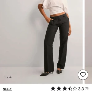 Svarta byxor från Nelly - Snygga svarta byxor från Nelly med låg midja och rak passform. Perfekta för en stilren look. Byxorna har en klassisk design med dragkedja framtill.