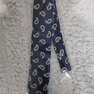 Mörkblå halsduk från Eton - Snygg mörkblå slips från Eton med ett stilrent paisleymönster i vitt. Perfekt för att ge en elegant touch till din outfit. Halsduken är förpackad i plast och är ny & oanvänd. 
