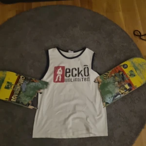 Vit ärmlös t-shirt från Ecko Unlimited - Säljer en vit ärmlös t-shirt från Ecko Unlimited med svart och röd grafik på både fram- och baksidan. Den har svarta kanter vid hals och ärmhål. Size medium
