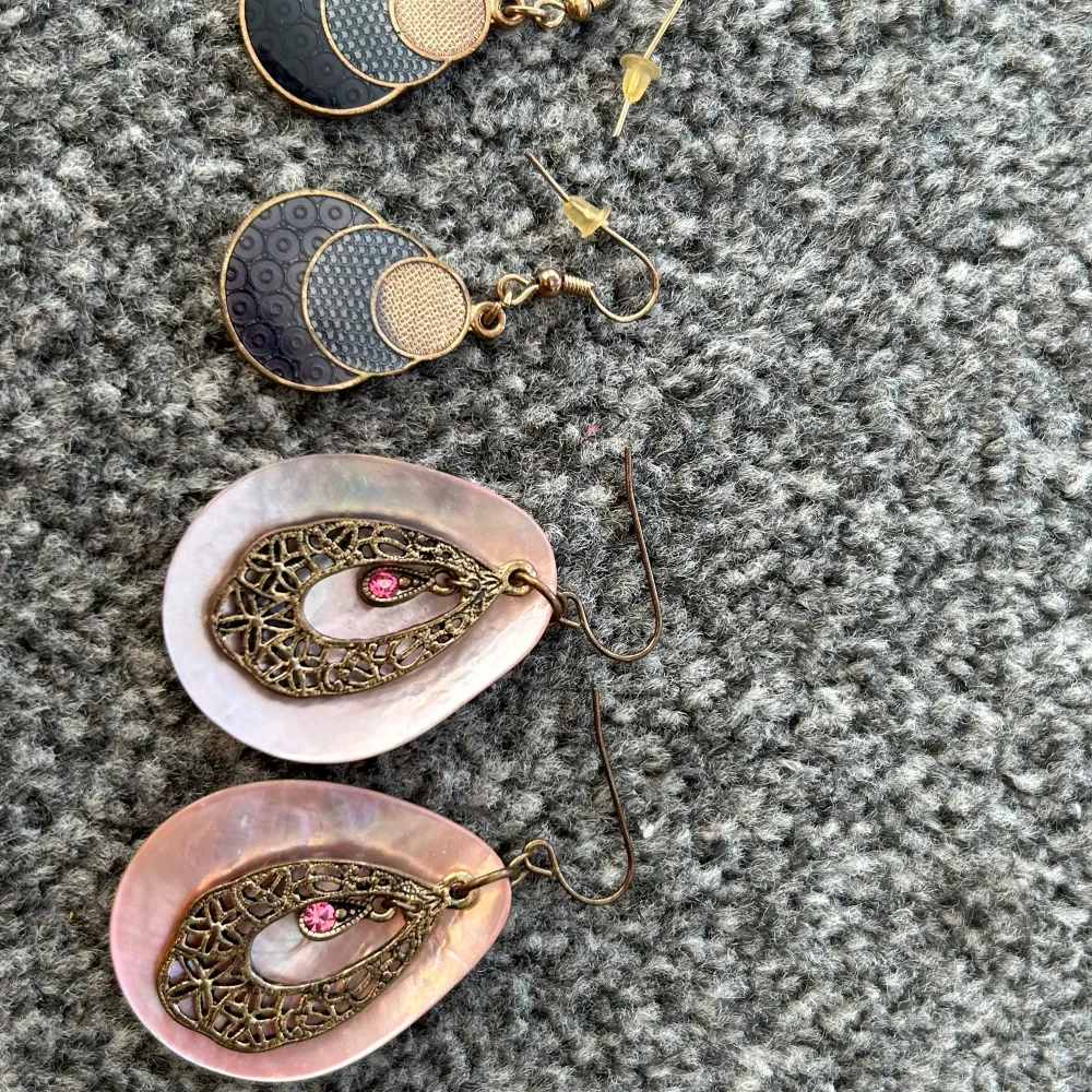 Säljer två par örhängen. Ett par i guld och svart med geometriskt mönster och ett par med rosa skal och antik guldfärgad metall med rosa stenar. Perfekt för att ge en unik touch till din outfit!. Asusteet.