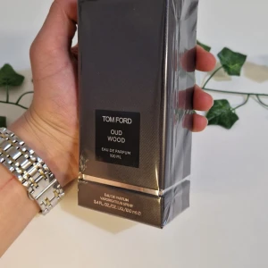 Tom Ford Oud Wood EDP 100ml - Säljer en lyxig Tom Ford Oud Wood Eau de Parfum i en elegant mörkgrå förpackning. Flaskan innehåller 100 ml av denna exklusiva doft som är känd för sina rika och träiga noter. Den är oöppnad och har plastet på. Nypris runt 3800kr.