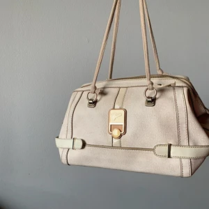 Beige handväska från Guess - Snygg beige handväska från Guess meddubbla handtag. Den är i bra skick. Om du vill ha mer bilder eller frågor så är de bara att fråga❤️